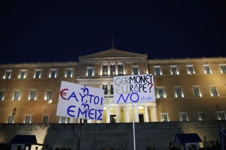 Protesters hold banners in front of the parliament building during an anti-austerity rally in Athens, Greece, June 29, 2015. REUTERS/Alkis Konstantinidis