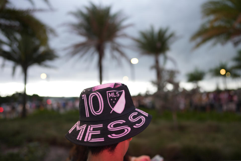A person wears a Lionel Messi hat as fans wait to enter DRV Pink Stadium, home of the Inter Miami MLS soccer team, for an event to present international superstar Lionel Messi one day after the team finalized his signing through the 2025 season, Sunday, July 16, 2023, in Fort Lauderdale, Fla. (AP Photo/Rebecca Blackwell)