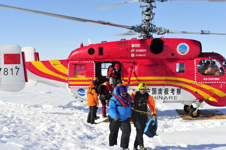 In this photo provided China's official Xinhnua News Agency, the first group of passengers of the trapped Russian ship MV Akademik Shokalskiy arrive at a safe surface off the Antarctic Thursday, Jan. 2, 2014. A helicopter rescued all 52 passengers from the research ship that has been trapped in Antarctic ice, 1,500 nautical miles south of Hobart, Australia, since Christmas Eve after weather conditions finally cleared enough for the operation Thursday. (AP Photo/Xinhua, Zhang Jiansong) NO SALES