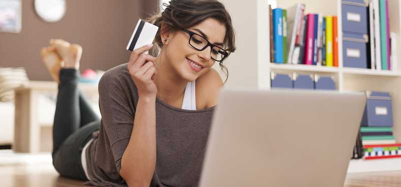 Woman holds credit card as she uses her laptop.