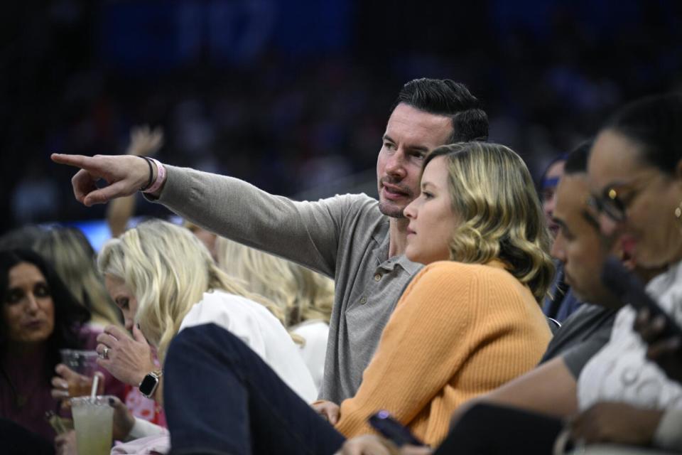 Former NBA guard JJ Redick (center) and his wife, Chelsea Kilgore, watch from courtside seats during a game in Orlando.