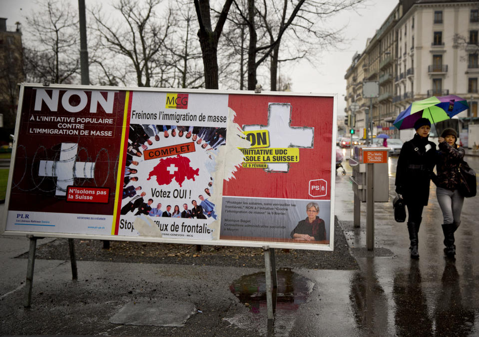 Women pass by election placards , poster in center is for a stop of immigration, and posters at left and at right are for a yes to immigration, in Geneva, Switzerland, Monday, Feb. 10, 2014. The placard in the center reads ' stop the influence from the border'. The choice by Swiss voters to reimpose curbs on immigration is sending shock waves throughout the European Union, with EU leaders on Monday warning the Swiss had violated the “sacred principle” of Europeans’ freedom of movement and politicians anxiously trying to gauge the vote’s impact on burgeoning anti-foreigner movements in other countries. (AP Photo/Anja Niedringhaus)