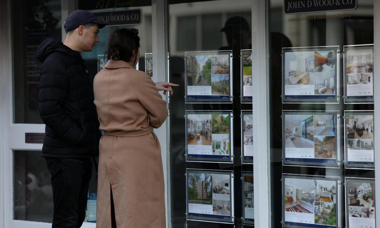 <span>People look at properties displayed in the window of a real estate agent's office in London.</span><span>Photograph: Hollie Adams/Reuters</span>