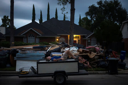 A boy lies on furniture on the back of a trailer while passing debris outside a house flooded by Tropical Storm Harvey in Houston, Texas, U.S. September 4, 2017. REUTERS/Adrees Latif