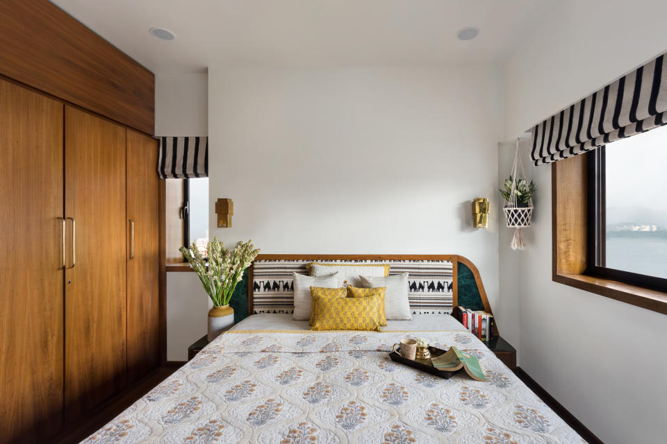 The guest bedroom is cosy with teak furniture and wood detailing. The headboards in both bedrooms feature soft furnishings that add colour and pattern to an otherwise neutral palette.