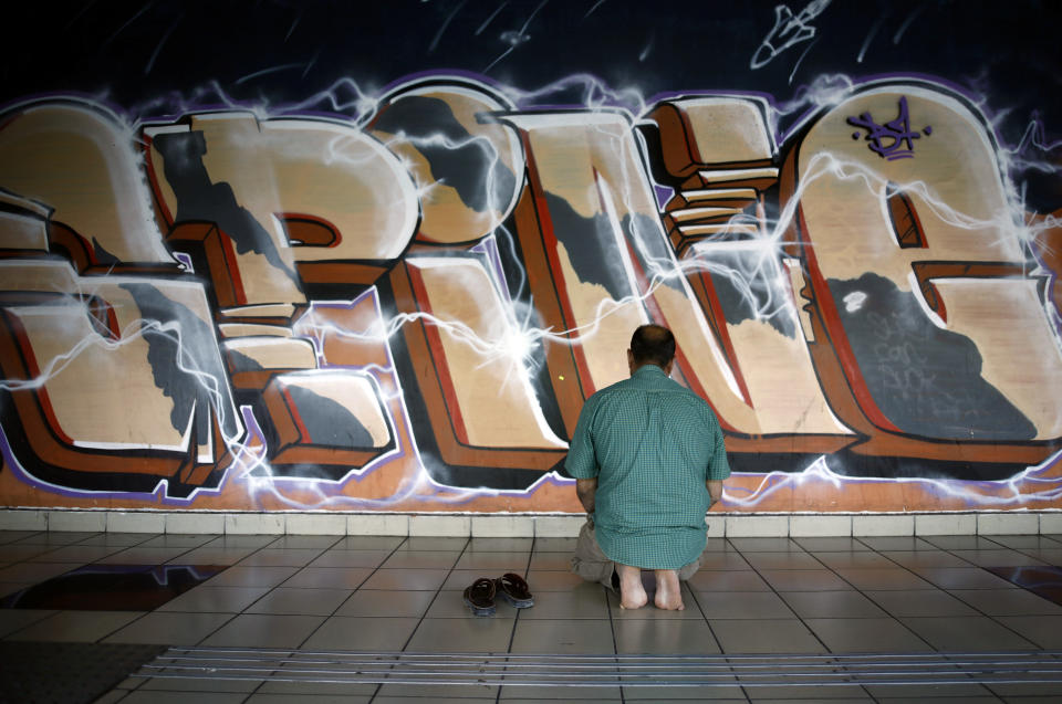 A Muslim man prays near graffiti at the Central Bus Station on May 29. (Photo: Corinna Kern/Reuters)