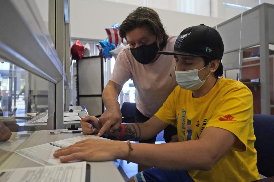 Ramiro Saez, left, helps his son Lucas Saez, 22, fill out a voter registration form, Tuesday, Oct. 6, 2020, at the Miami-Dade County Elections Department in Doral, Fla. Florida Gov. Ron DeSantis extended the state's voter registration deadline after heavy traffic crashed the state's online system and potentially prevented thousands of enrolling to cast ballots in next month's presidential election. Saez attempted to register to vote six times the night before without any luck. (AP Photo/Wilfredo Lee)