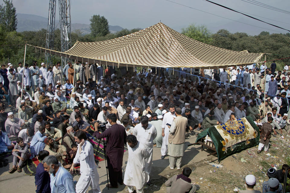 Relatives and residents gather with the body of a school van driver who was killed by a gunman in an attack Monday, as they block a road during a protest demanding the immediate arrest of the attacker, in Mingora, Swat Valley, Pakistan, Tuesday, Oct. 11, 2022. Thousands of people protested in northwest Pakistan on Tuesday after the attack killed the driver and critically injured a child, a decade after schoolgirl Malala Yousufzai was shot by the Taliban in the same city. (AP Photo/Sherin Zada)