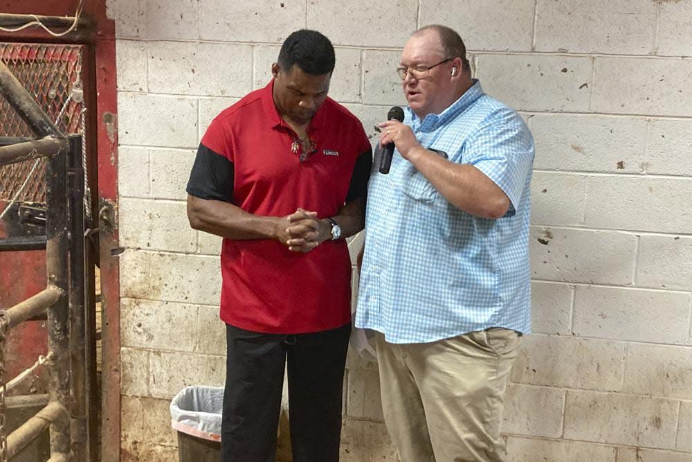 Georgia Republican Senate candidate Herschel Walker prays with a supporter at a livestock auction outside Athens, Ga., on July 20, 2022. (AP Photo/Bill Barrow, File)