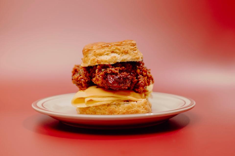 The Crispy Chicken, Egg and Cheese Biscuit at Kinfolk diner in Memphis. A biscuit is stuffed with a crispy chicken thigh dipped in hot honey, eggs, cheddar cheese, Kinfolk's signature breaky sauce and chives.