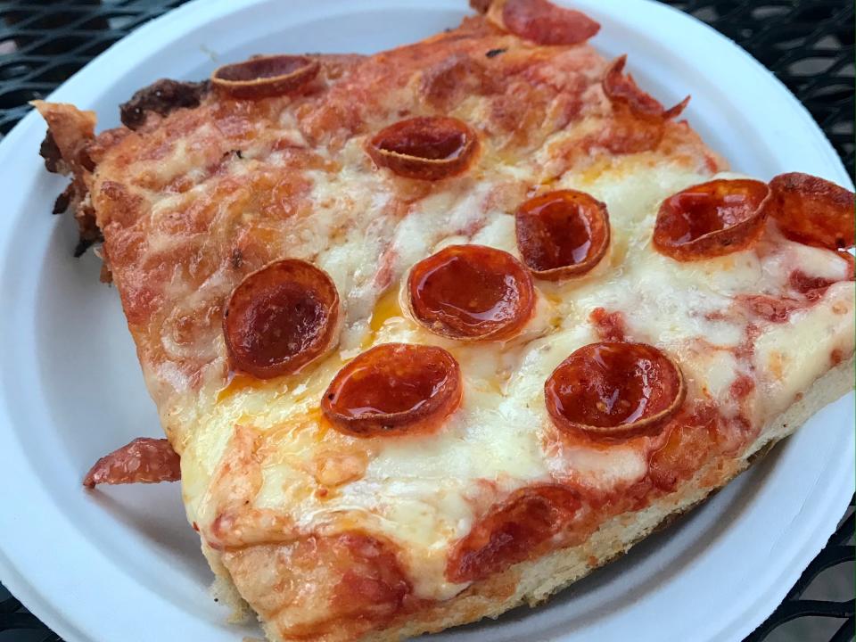 square slice of pizza with pepperoni on a paper plate from italy in epcot