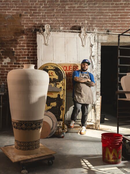Roberto Lugo poses in his Philadelphia studio with an in-progress work, an urn that he’s since completed for his new exhibition, <i>The Gilded Ghetto, </i>now on display at R & Company in New York. The urn is a focal point of the show and a key component of his Peacock Room installation, Lugo’s interpretation of painter James McNiell Whistler’s period room of the same name at the Freer Gallery of Art in Washington, D.C.