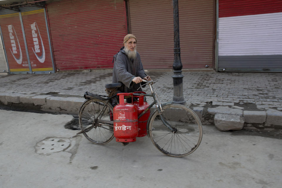 A Kashmiri man transports empty cooking gas cylinders on a bicycle as he walks past a closed market during a strike in Srinagar, Indian controlled Kashmir, Thursday, Feb. 28, 2019. As tensions escalate between India and Pakistan, shops and business remained closed for the second consecutive day in Indian portion of Kashmir following a strike call by separatist leaders to protest Tuesday's raids on key separatist leaders by Indian intelligence officers. (AP Photo/ Dar Yasin)