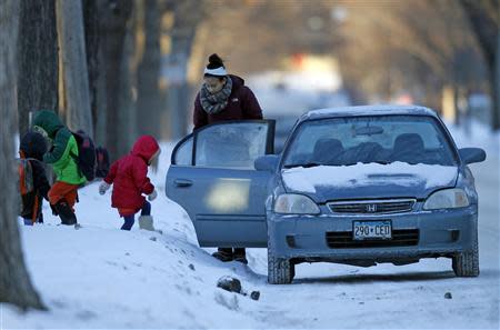 Kids climb into a car to be driven to school in sub-zero temperatures in Minneapolis, January 8, 2014. REUTERS/Eric Miller