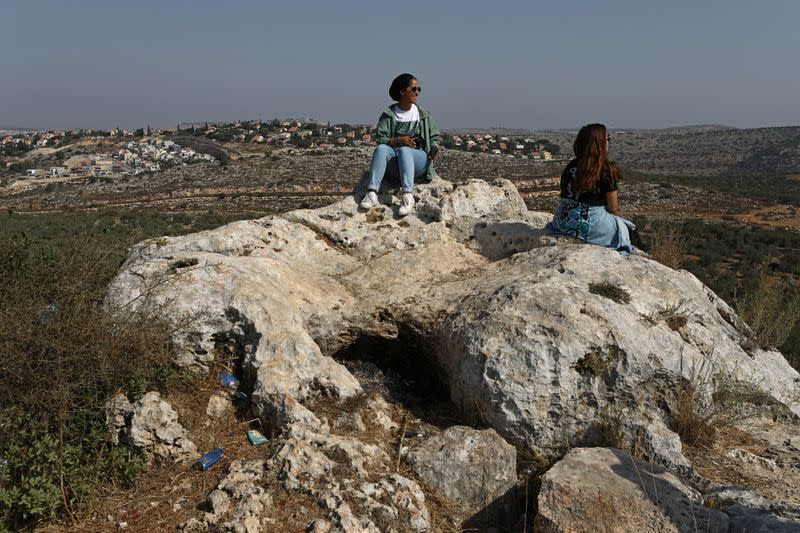 Las jóvenes blogueras de viajes Malak Hasan y Bisan Alhajhasan se sientan en los restos de un sitio arqueológico en la aldea de Aboud, cerca de Ramallah, Cisjordania, Palestina