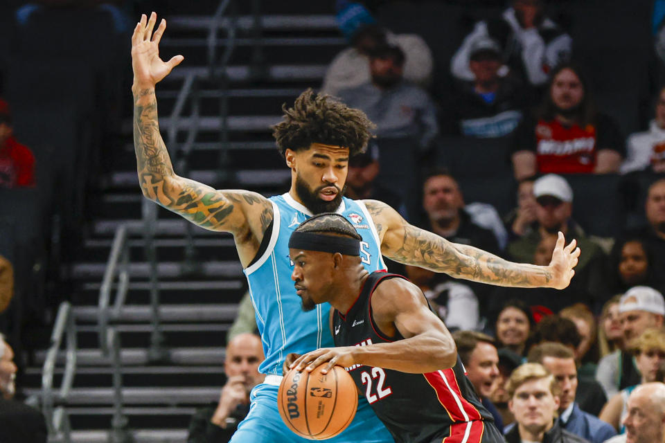 Miami Heat forward Jimmy Butler (22) drives into Charlotte Hornets center Nick Richards, top, during the first half of an NBA basketball game in Charlotte, N.C., Monday, Dec. 11, 2023. (AP Photo/Nell Redmond)