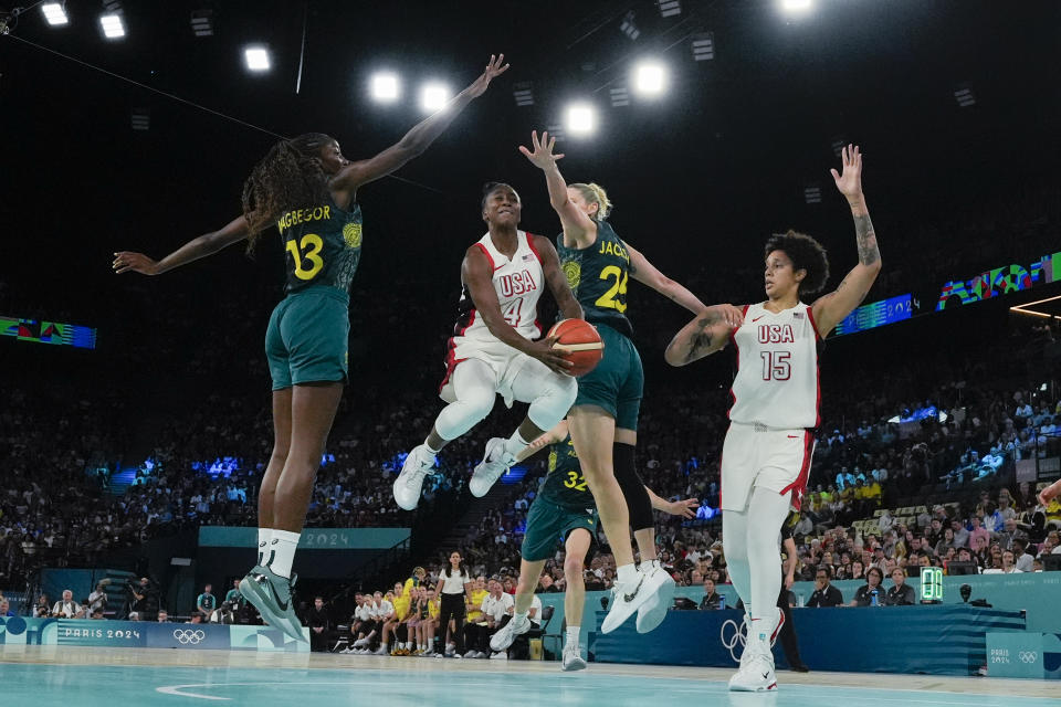 United States' Jewell Loyd (4) hangs in the air as she goes up against Ezi Magbegor (13), of Australia, and Lauren Jackson (25), of Australia, during a women's semifinal basketball game at Bercy Arena at the 2024 Summer Olympics, Friday, Aug. 9, 2024, in Paris, France. (AP Photo/Michael Conroy)