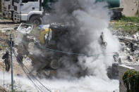 Smoke rises following an explosions raises as Israeli soldiers take cover during a military operation in the Palestinians town of Deir al-Ghusun, near the West Bank town of Tulkarem, Saturday, May 4, 2024. (AP Photo/Majdi Mohammed)