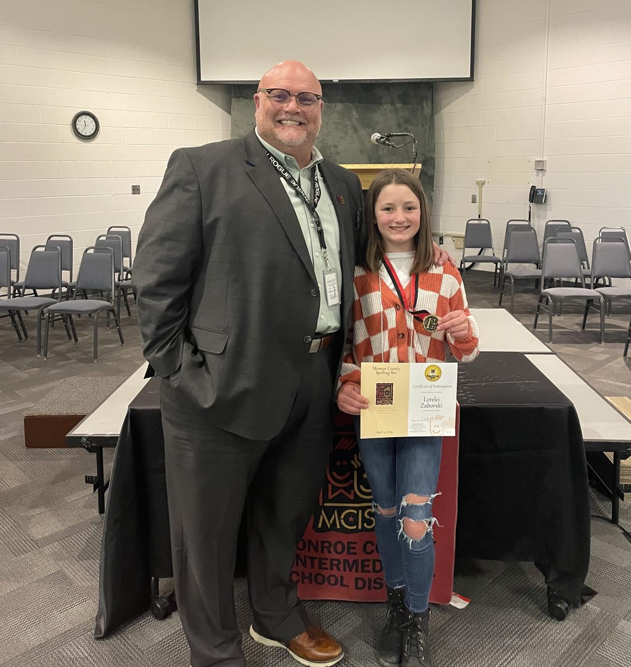 Monroe County Intermediate School District Superintendent Stephen McNew congratulates Lorelei Zaborski of Dundee Middle School. Zaborski placed first in the fifth and sixth grade category at the 2024 Monroe County Spelling Bee.