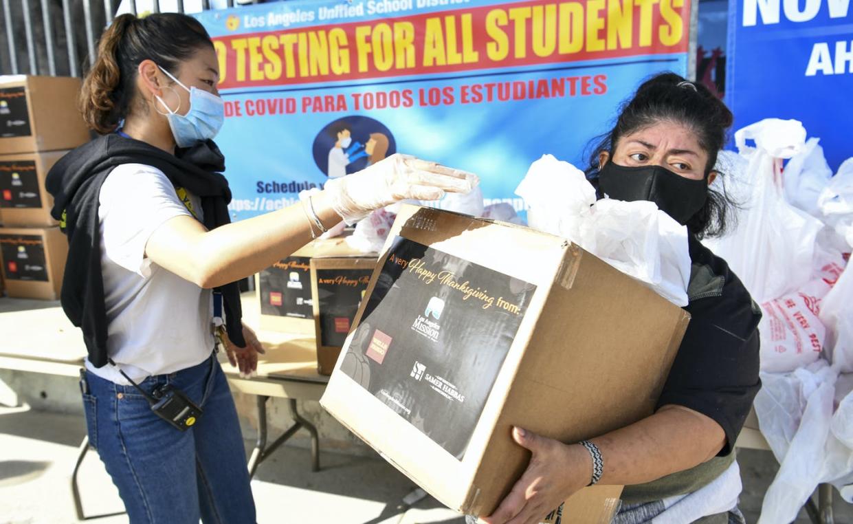 <span class="caption">A volunteer hands out food boxes in Los Angeles before Thanksgiving.</span> <span class="attribution"><a class="link " href="https://www.gettyimages.com/detail/news-photo/volunteer-hands-out-food-boxes-during-the-los-angeles-news-photo/1286744824?adppopup=true" rel="nofollow noopener" target="_blank" data-ylk="slk:Rodin Eckenroth/Getty Images;elm:context_link;itc:0;sec:content-canvas">Rodin Eckenroth/Getty Images</a></span>