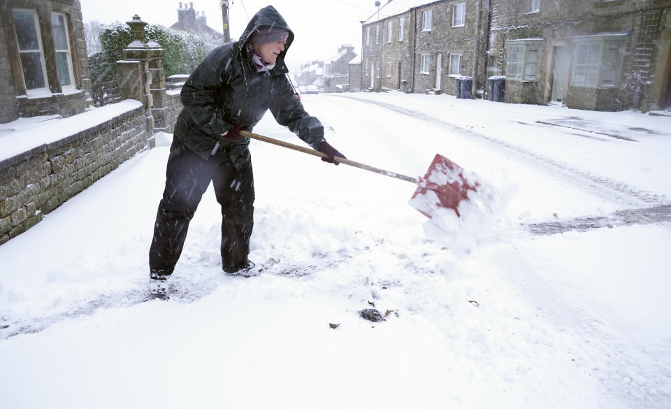 A resident clears a path in Bowes, Durham, as heavy snow falls.