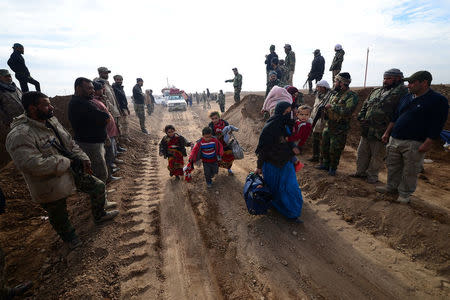 Displaced people, fleeing the violence of Islamic State militants in outskirts of Sinjar, walk past Shiite fighters in Sinjar, Iraq, December 5, 2016. REUTERS/Stringer