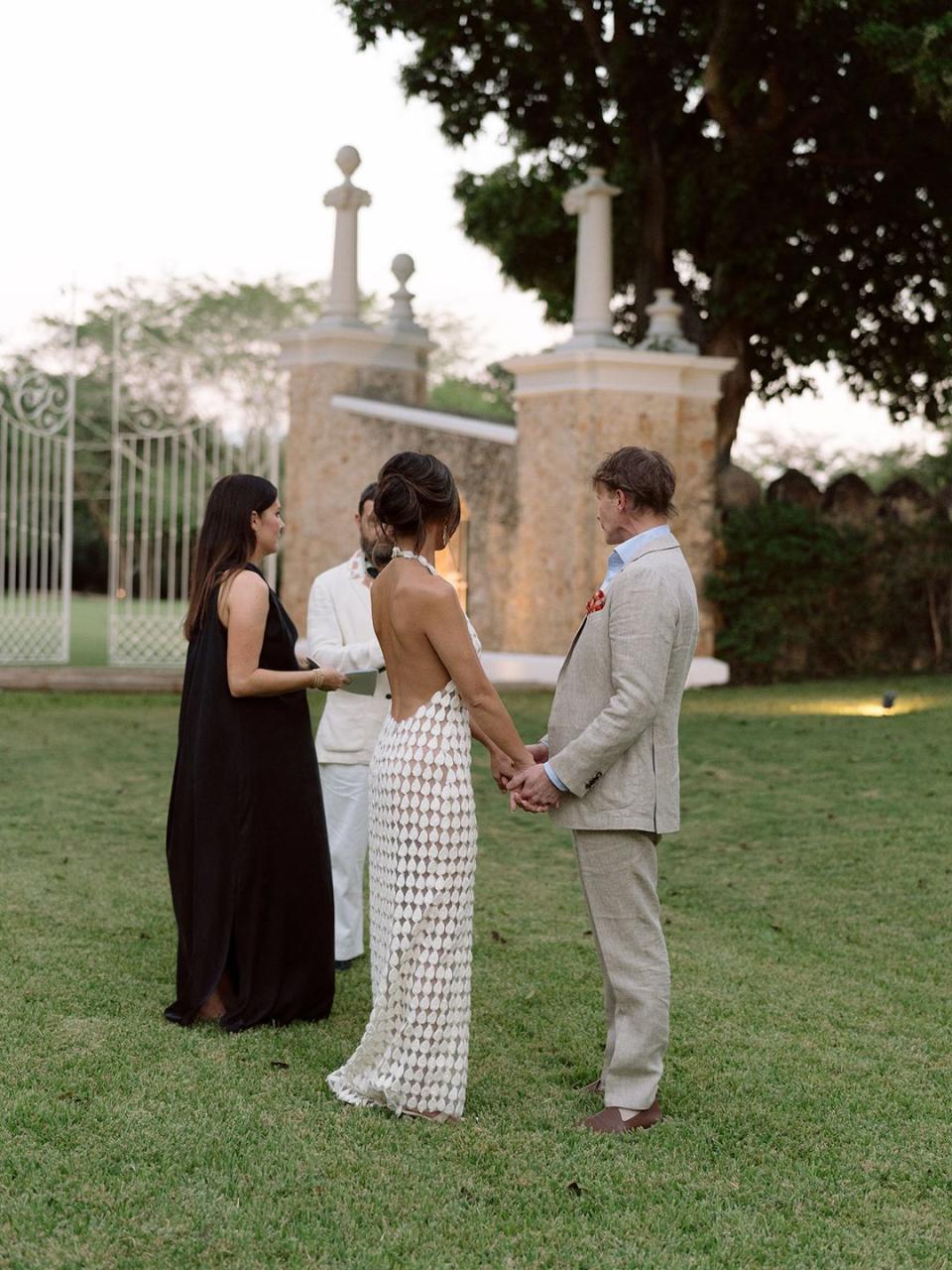 a group of people standing in a grassy area with a statue in the background