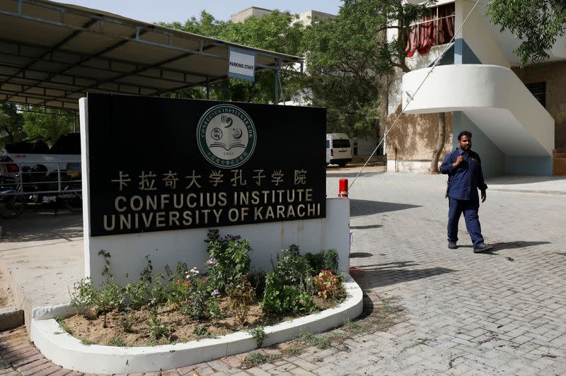 A security guard walks after a blast near a passenger van at the entrance of the Confucius Institute University of Karachi