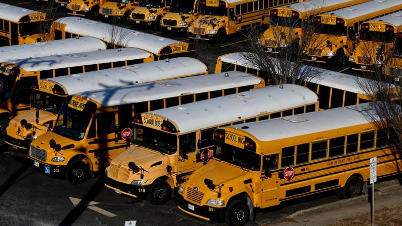 Numerous yellow school buses parked in a holding lot.
