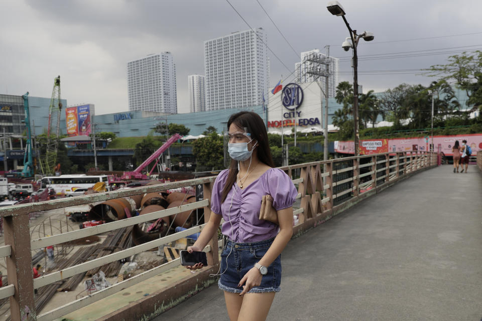 A woman wearing a face mask and shield to prevent the spread of the coronavirus walks outside a mall in Quezon City, Philippines on Monday, Feb. 15, 2021. The Philippine government's approval for reopening many movie theaters, video game arcades and other leisure businesses closed since last year was postponed at least another two weeks after mayors feared it will bring new coronavirus infections. (AP Photo/Aaron Favila)