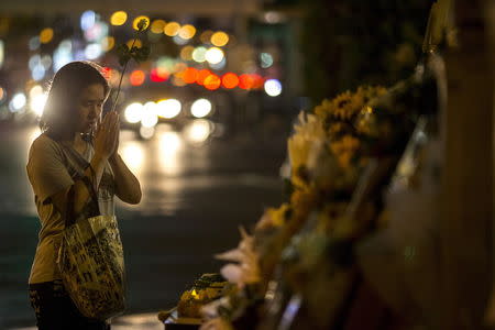A woman holds up a flower as she prays at the Erawan shrine, the site of Monday's deadly blast, in central Bangkok, Thailand, August 20, 2015. REUTERS/Athit Perawongmetha