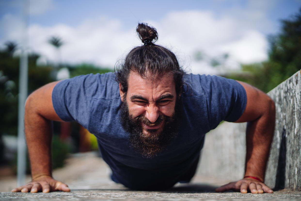 Front view of a man doing push ups on the ground outdoors at daylight