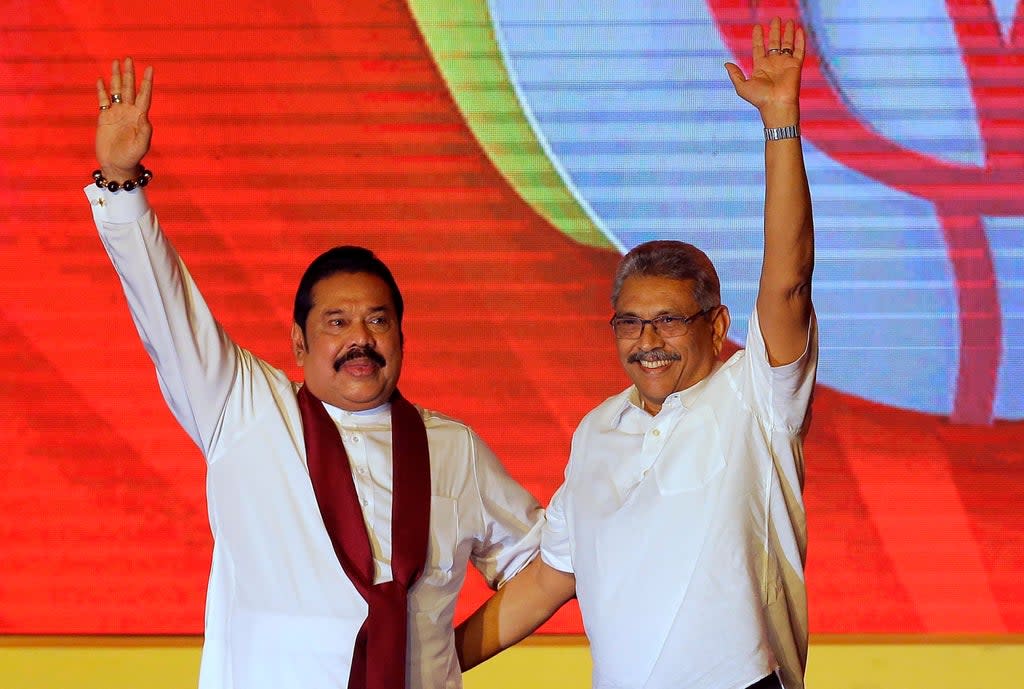 Mahinda Rajapaksa (left) and his brother Gotabaya Rajapaksa wave to supporters during a party convention in 2019  (AP)