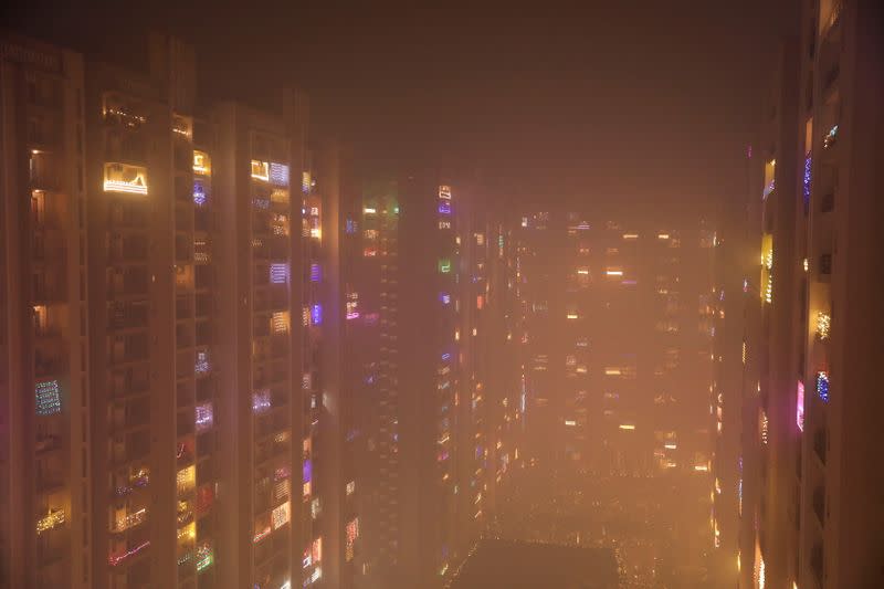 Lights decorating the balconies of a high-rise are seen shrouded in smog, in Noida