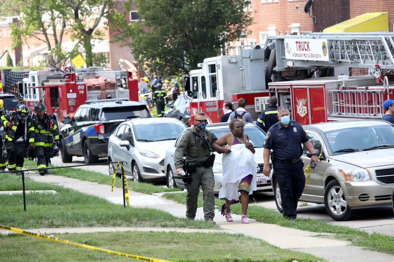 Police officers help a woman at the scene of an explosion in a residential area of Baltimore