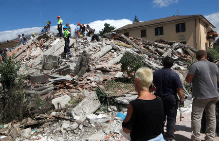Rescuers and people stand next a collapsed building following an earthquake in Amatrice, central Italy, August 24, 2016. REUTERS/Ciro De Luca