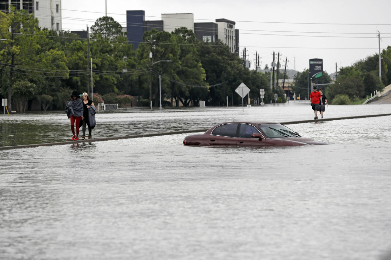 Evacuees walk along a median of Interstate 610 covered in floodwaters from Hurricane Harvey. (AP Photo/David J. Phillip)