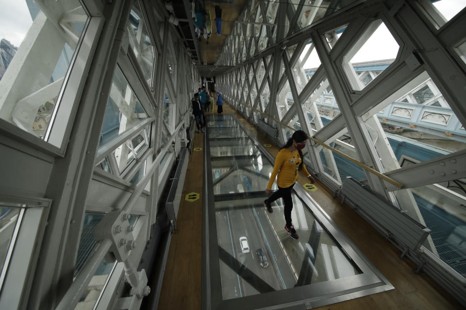 A visitor walks over the glass walkway at the Tower Bridge Visitor Attraction, in London, on the first day it was allowed to reopen as the British government relaxes its third coronavirus lockdown restrictions, Monday, May 17, 2021. (AP Photo/Matt Dunham)