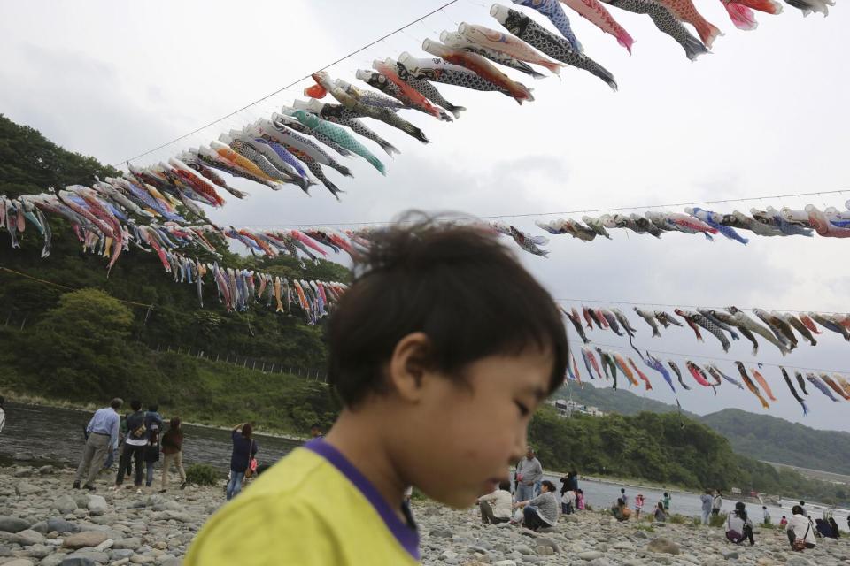 Boy walks under lines of colorful carp streamers