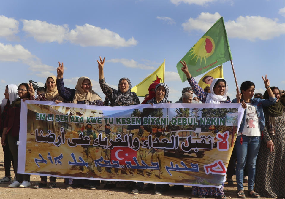Kurdish women hold a banner with Arabic that read, "We don't accept enemies and strangers on our land," as they protest against possible Turkish military operation on their areas, at the Syrian-Turkish border, in Ras al-Ayn, Syria, Monday, Oct. 7, 2019. Syria's Kurds accused the U.S. of turning its back on its allies and risking gains made in the fight against the Islamic State group as American troops began pulling back on Monday from positions in northeastern Syria ahead of an expected Turkish assault. (AP Photo)