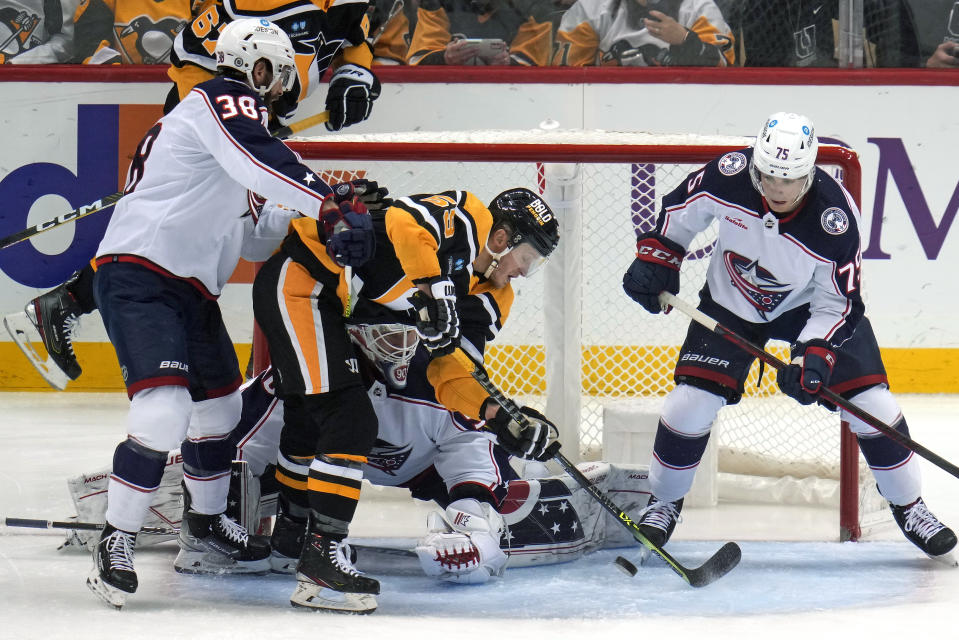 Pittsburgh Penguins' Jake Guentzel, center, can't get his stick on a rebound in front of Columbus Blue Jackets goaltender Elvis Merzlikins, with Boone Jenner (38) and Tim Berni (75) defending during the first period of an NHL hockey game in Pittsburgh, Tuesday, Dec. 6, 2022. (AP Photo/Gene J. Puskar)