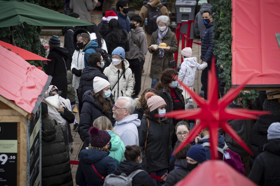 People wear face masks to curb the spread of COVID-19 while visiting the Christmas Market in Vancouver, British Columbia, Thursday, Dec. 23, 2021. (Darryl Dyck/The Canadian Press via AP)