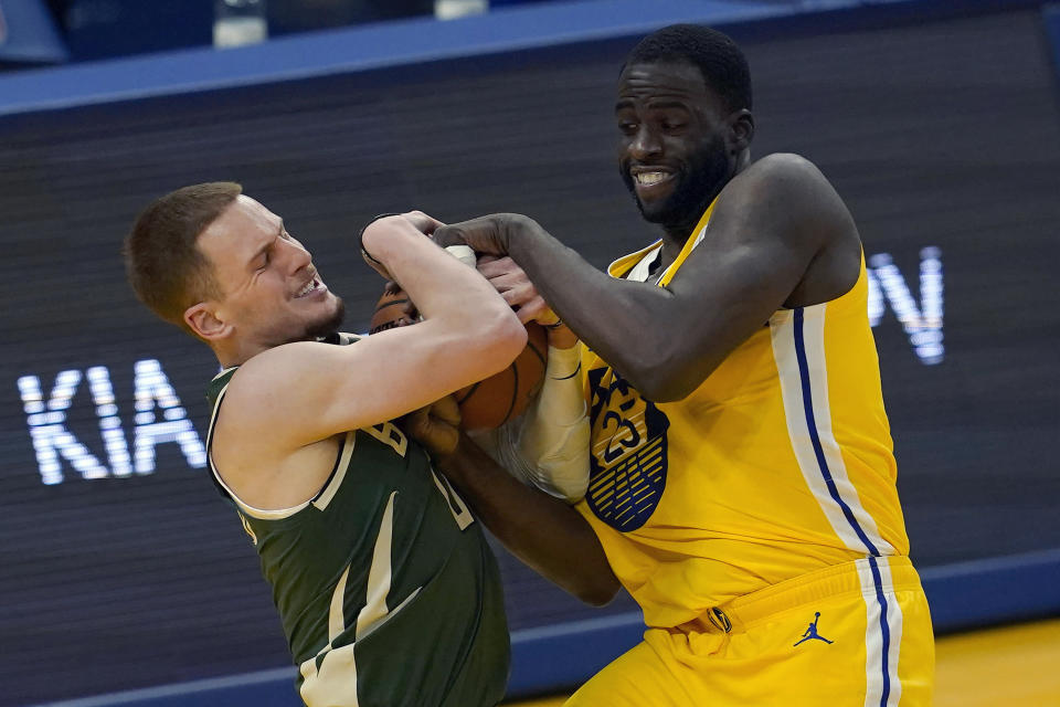 Milwaukee Bucks guard Donte DiVincenzo, left, tries to control the ball against Golden State Warriors forward Draymond Green during the first half of an NBA basketball game in San Francisco, Tuesday, April 6, 2021. (AP Photo/Jeff Chiu)