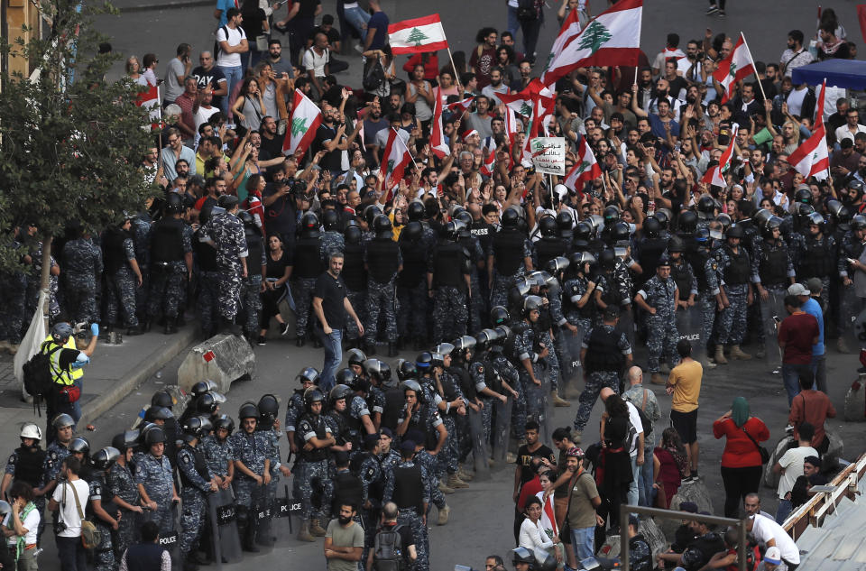 Lebanese riot policemen stand guard between anti-government protesters and Hezbollah supporters after they clash between each other during a protest near the government palace, in downtown Beirut, Lebanon, Friday, Oct. 25, 2019. Hundreds of Lebanese protesters set up tents, blocking traffic in main thoroughfares and sleeping in public squares on Friday to enforce a civil disobedience campaign and keep up the pressure on the government to step down. (AP Photo/Hussein Malla)