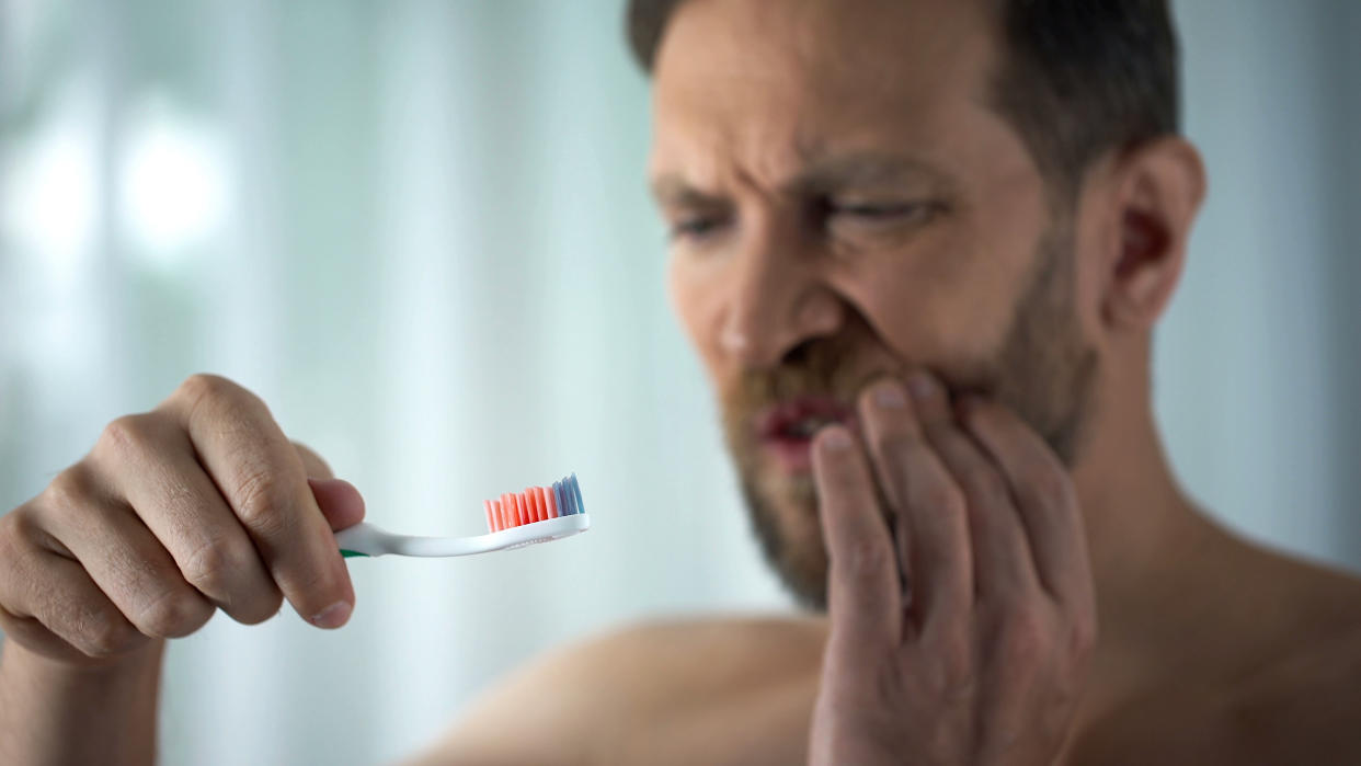 Male in bathroom looking at blood toothbrush, oral hygiene, parodontosis illness