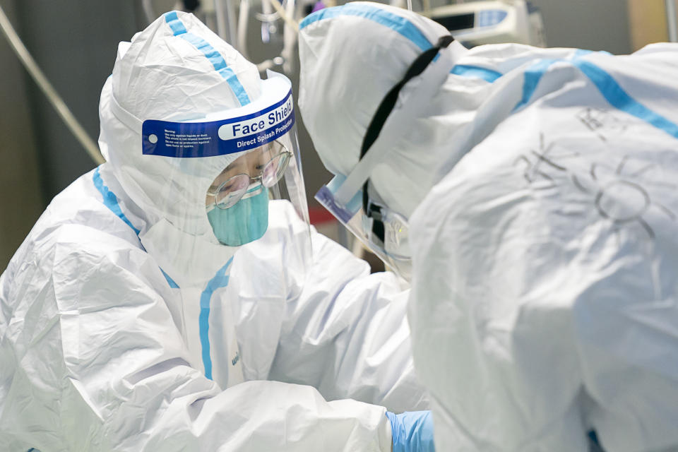 En esta fotografía proporcionada por la agencia de noticias china Xinhua, unos trabajadores médicos atienden a un paciente en el Hospital Zhongnan, en Wuhan, China. (Xiong Qi/Xinhua vía AP)