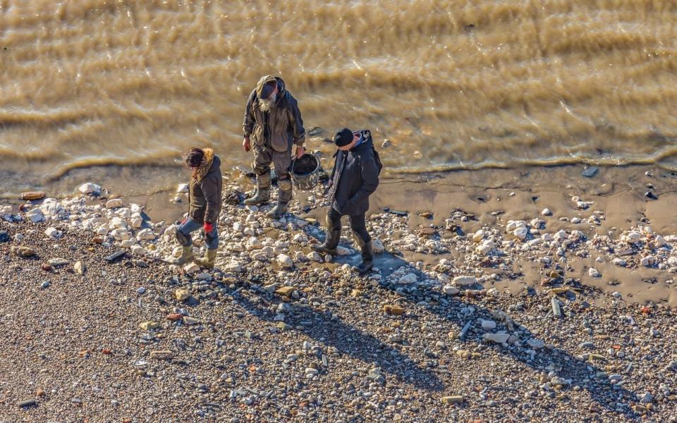 Three mudlarks searching along the foreshore of the River Thames in London - Istock