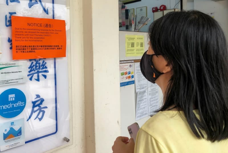 A woman reads a notice sign about "overwhelming response" for the Sinovac vaccine at a clinic, during the coronavirus disease (COVID-19) outbreak in Singapore