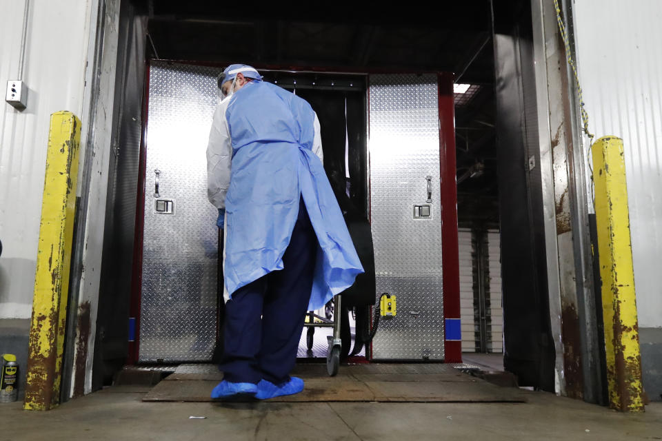 In this Tuesday, May 5, 2020, photo, Cook County Medical Examiner forensic technician Pero Paunovich wheels the body of a COVID-19 victim from an emergency-management truck that just arrived at the medical examiner's auxiliary surge storage center in Chicago. An encouraging sign amid the grimness is that two of the rooms are mostly empty, an indication the medical examiner's system to ensure most bodies are released to funeral homes as quickly as possible is working. (AP Photo/Charles Rex Arbogast)