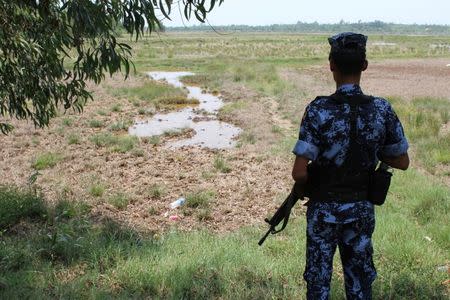 FILE PHOTO: A Myanmar border guard stands guard near the Taung Pyo Letwe reception camp overlooking the border with Bangladesh, in Rakhine state, Myanmar, during a trip by United Nations envoys to the region, May 1, 2018. REUTERS/Michelle Nichols